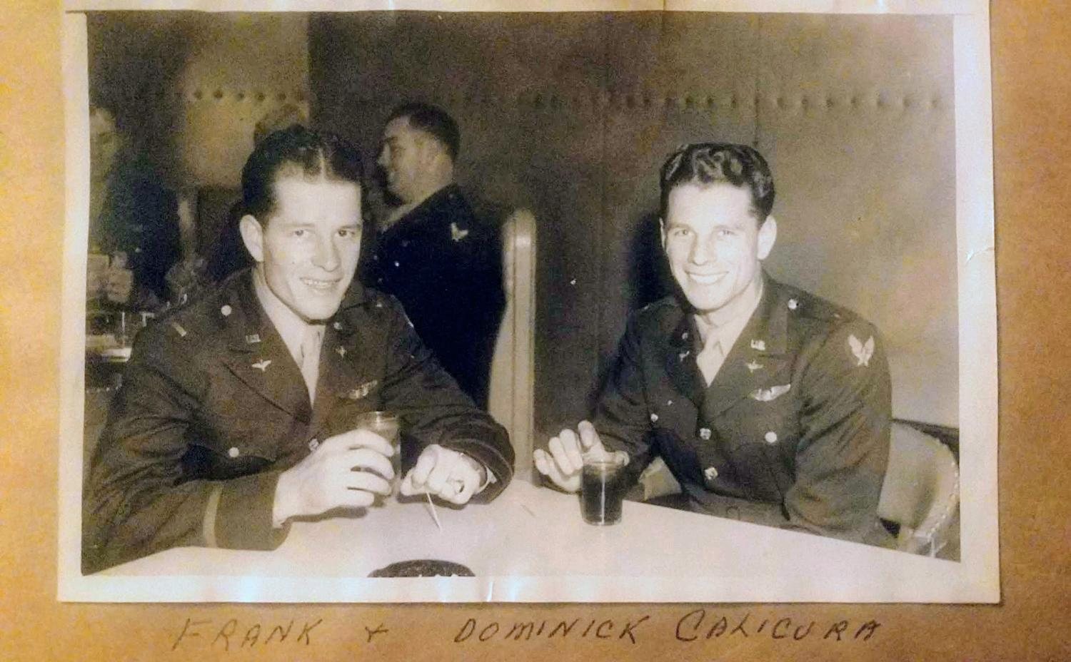 Frank and Dominic Calicura in officer’s uniforms at a table, glasses in hand, the album page captioned Frank and Dominick Calicura