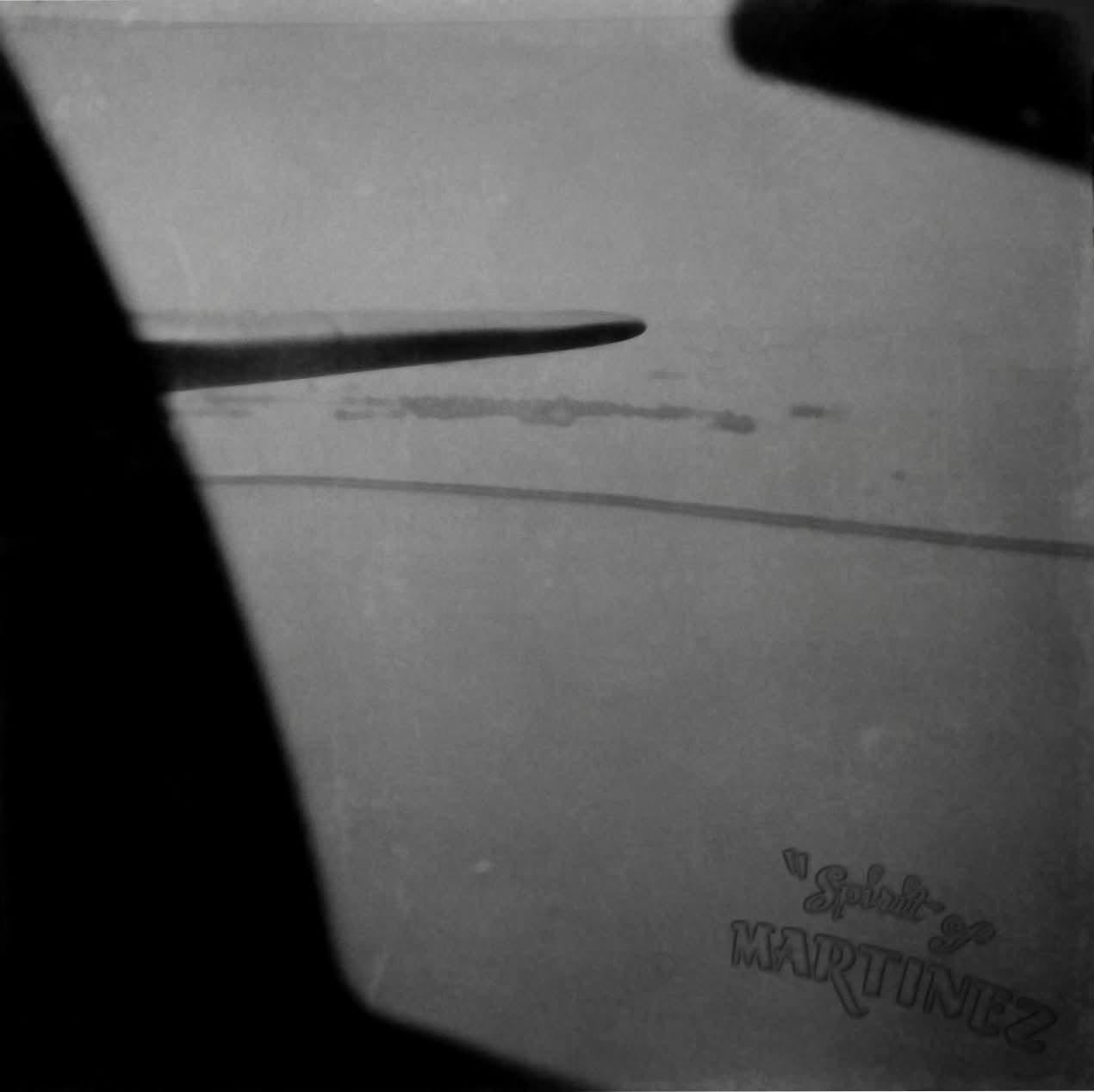 View through a B-17 window: another aircraft’s wing against pale sky, Spirit of Martinez lettered on the print later