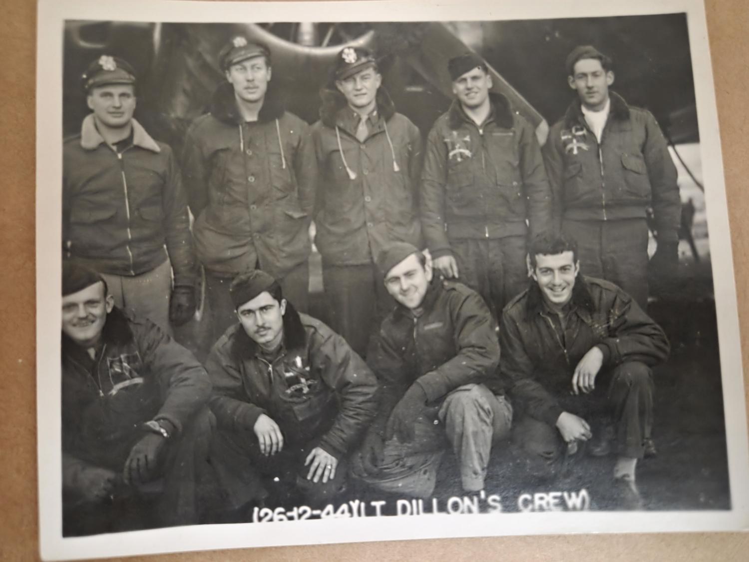 Nine airmen in flight jackets posed in two rows under a B-17, the print labeled 26-12-44 Lt. Dillon’s Crew