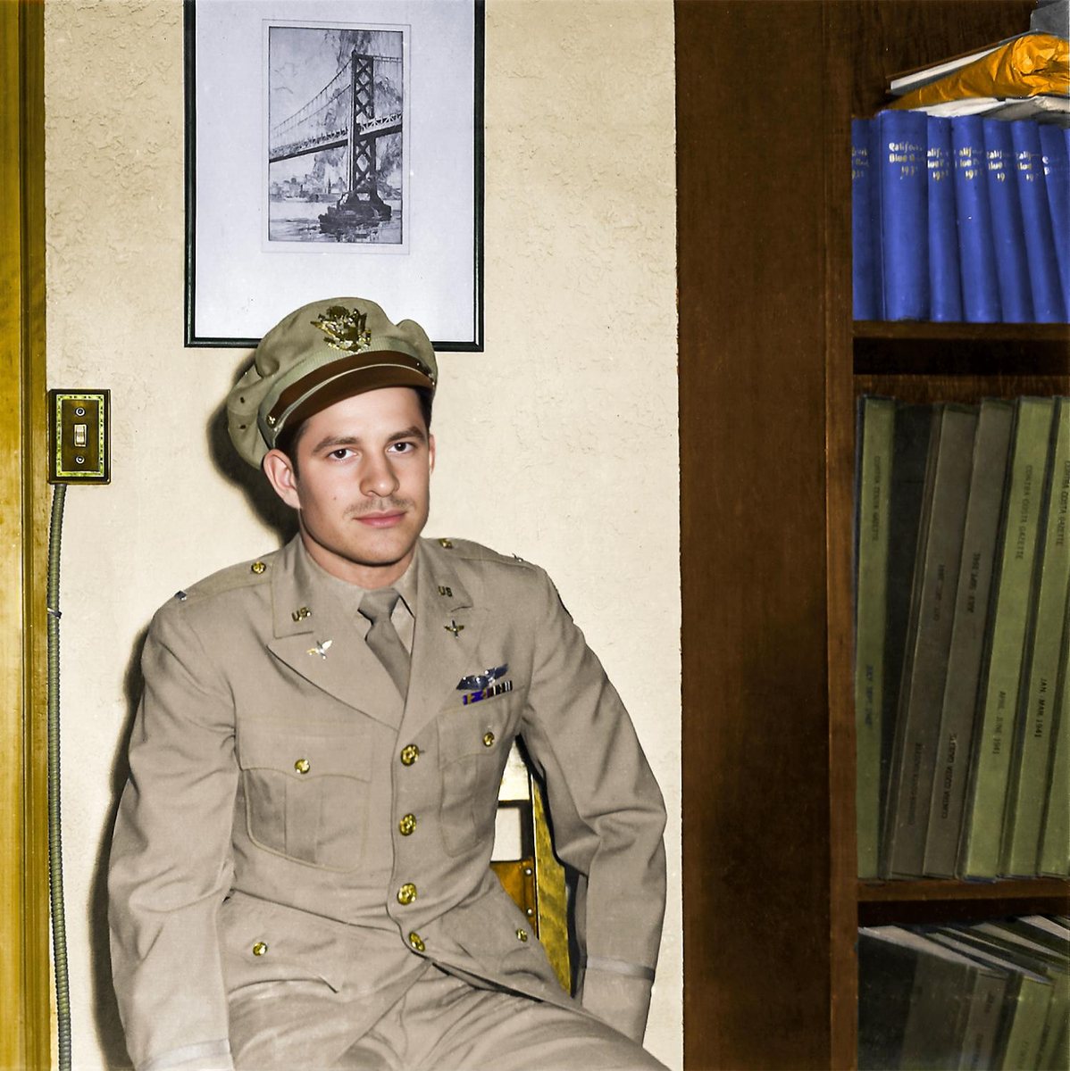 First Lieutenant Frank Calicura in khaki uniform seated beside bound volumes of the Contra Costa Gazette