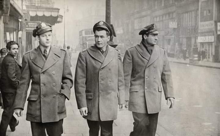 Three American officers in greatcoats walking Oxford Street, the Mindel & Faraday shopfront behind them