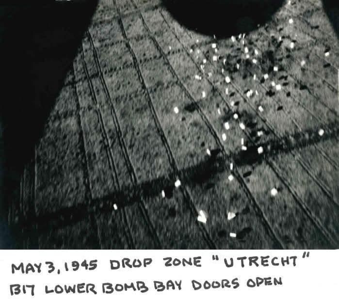 Looking down through open B-17 bomb bay doors at white sacks falling onto a field, labeled May 3 1945 drop zone Utrecht
