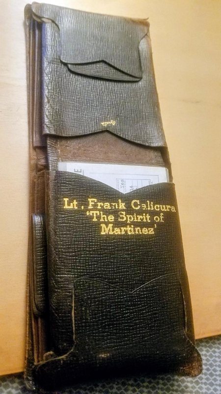 A worn black leather wallet stamped in gold Lt. Frank Calicura The Spirit of Martinez